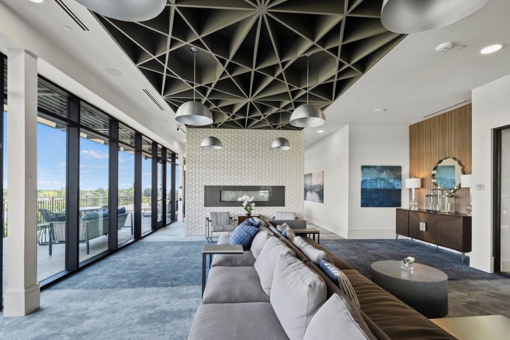 A modern living room with a grey sofa and a large window.