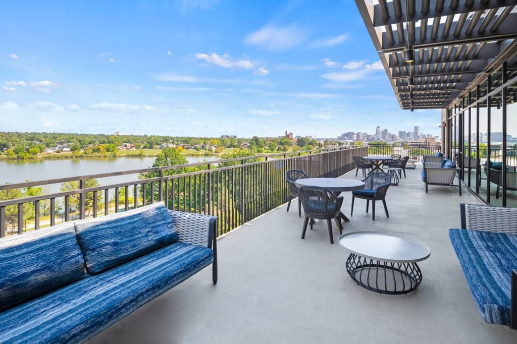 A balcony with a table and chairs overlooking a river.