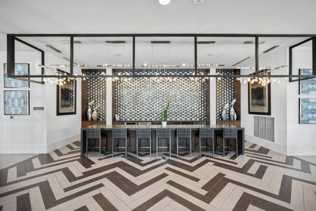 A modern bar area with a patterned floor and a backdrop of framed pictures.