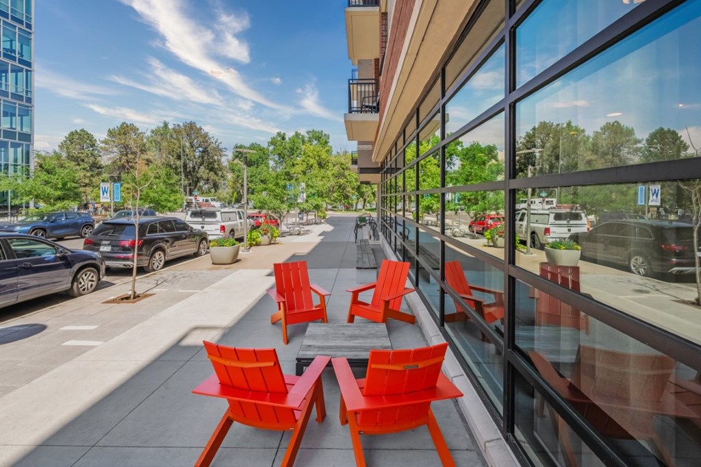A glass building with red chairs and tables outside.