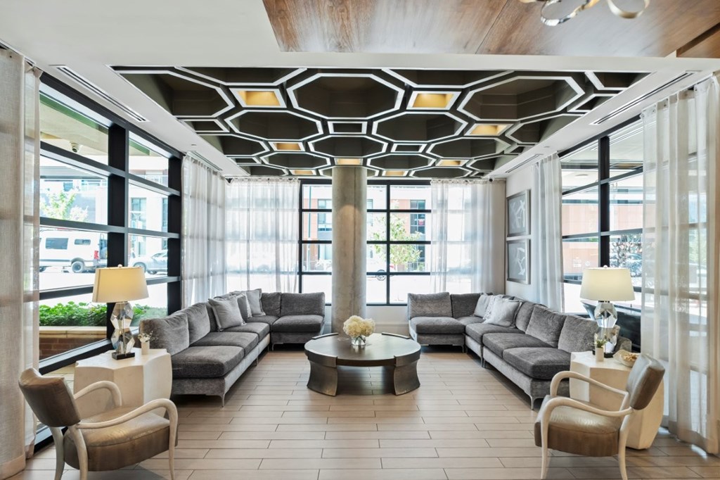 A large, modern living room with a long grey sofa and a coffee table in the middle.