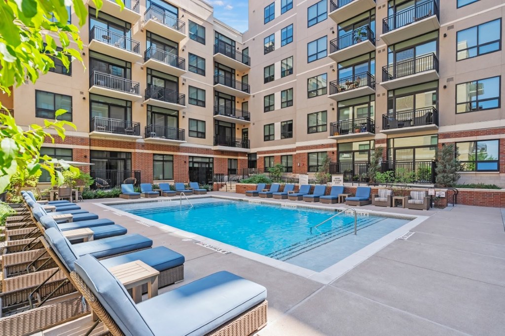 A large outdoor pool with lounge chairs and a building in the background.