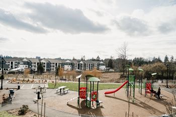 a playground in a park with apartment buildings in the background