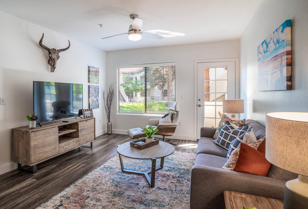 a living room with a grey couch and a tv on top of a wooden stand