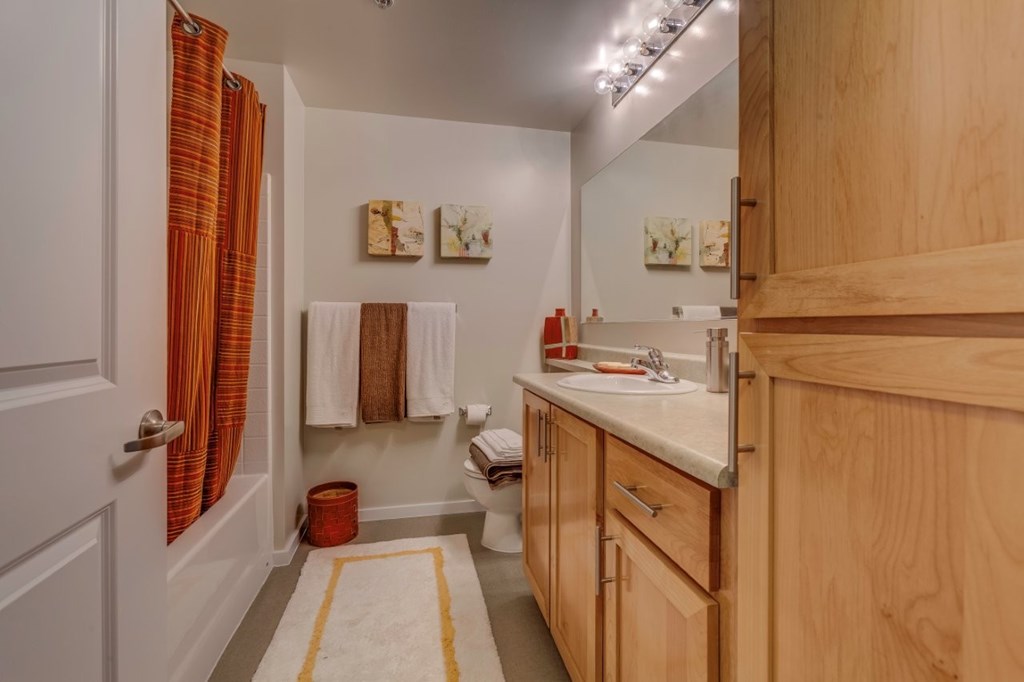 A bathroom with wooden cabinets and a white sink.
