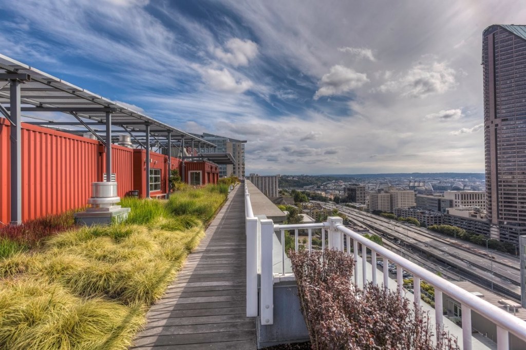 A walkway with a metal railing leads to a cityscape.
