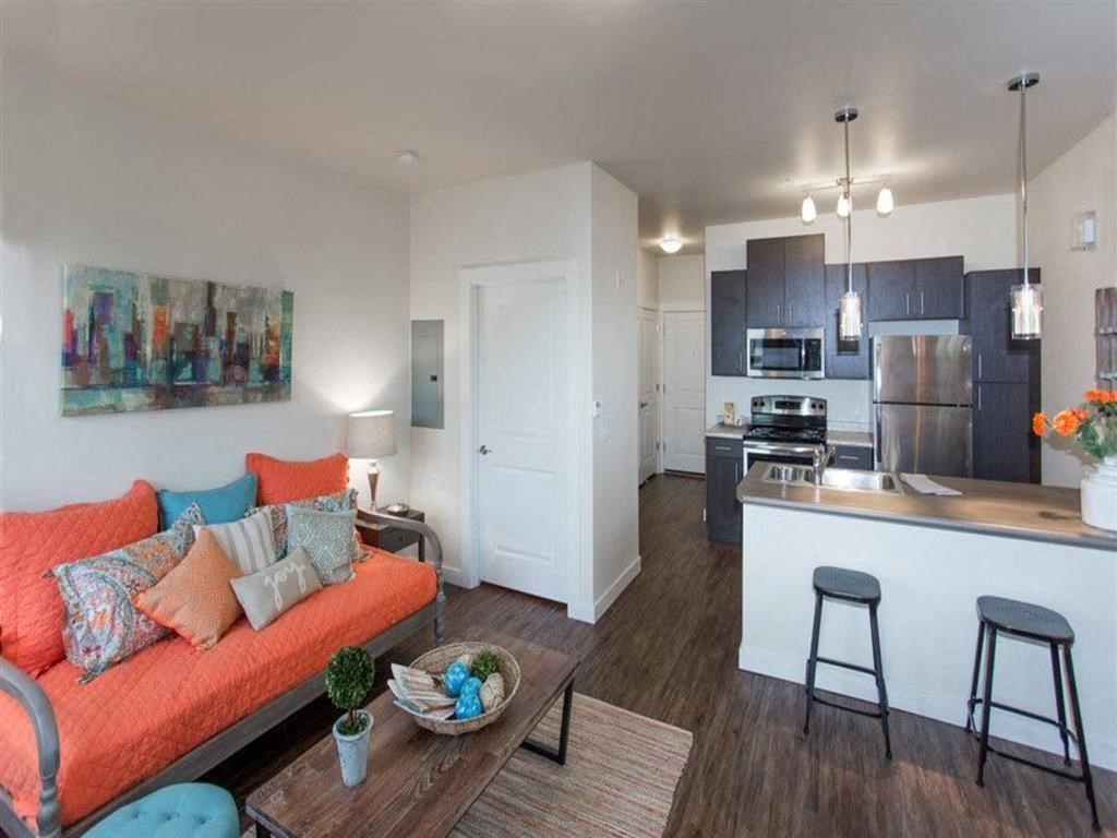 a living room with an orange couch and a kitchen