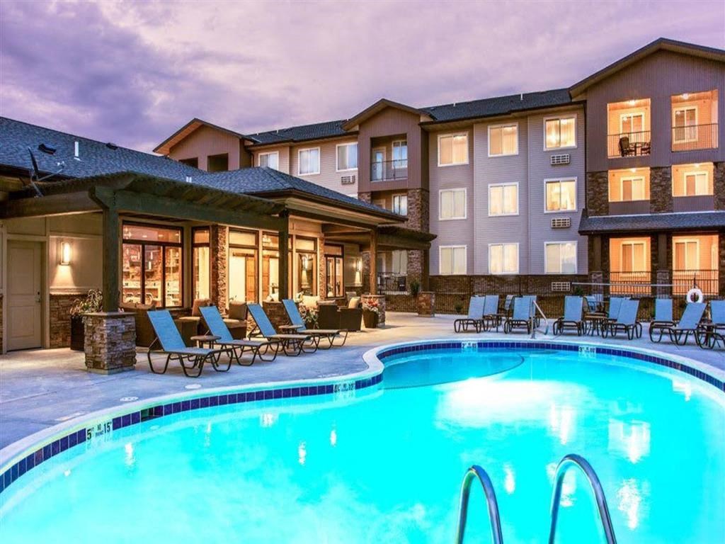 a swimming pool with chairs in front of a hotel