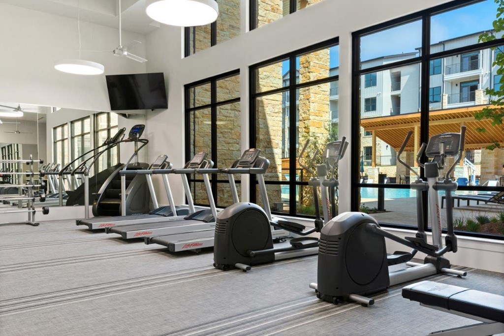 a gym with cardio equipment and windows in a building