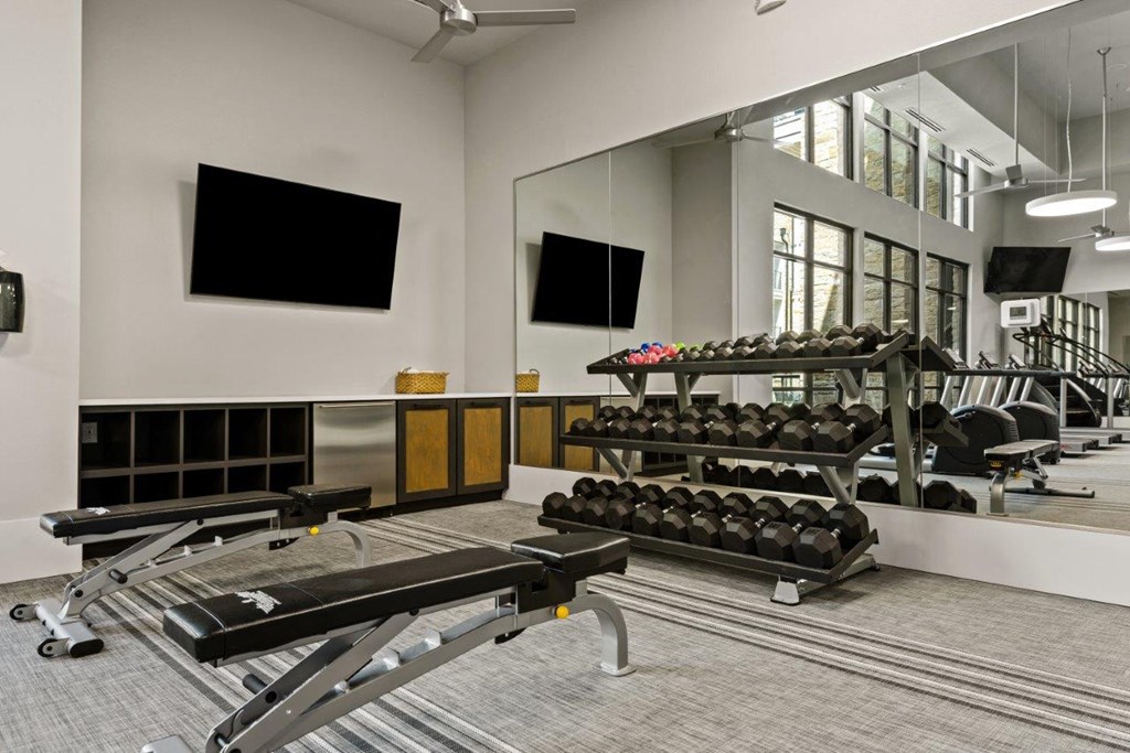 a gym with weights and mirrors in front of a large mirror