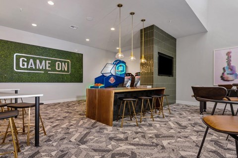 a game room with a bar and chairs and a game on screen