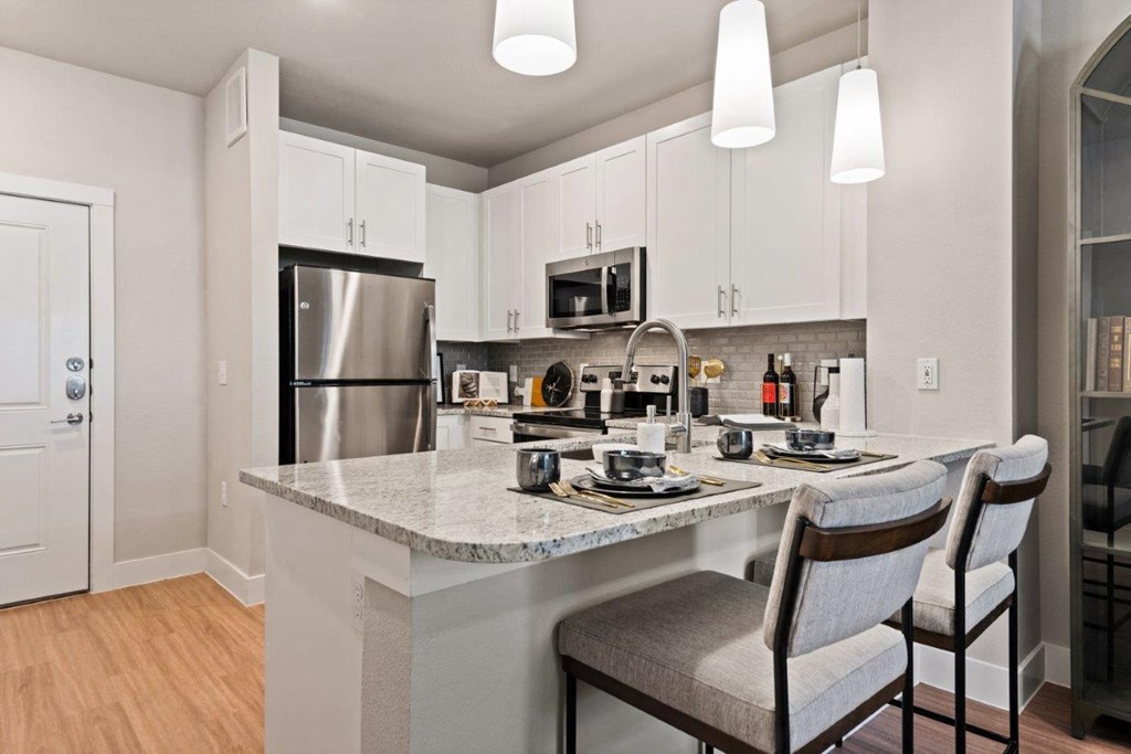 a kitchen with a marble counter top and a stainless steel refrigerator
