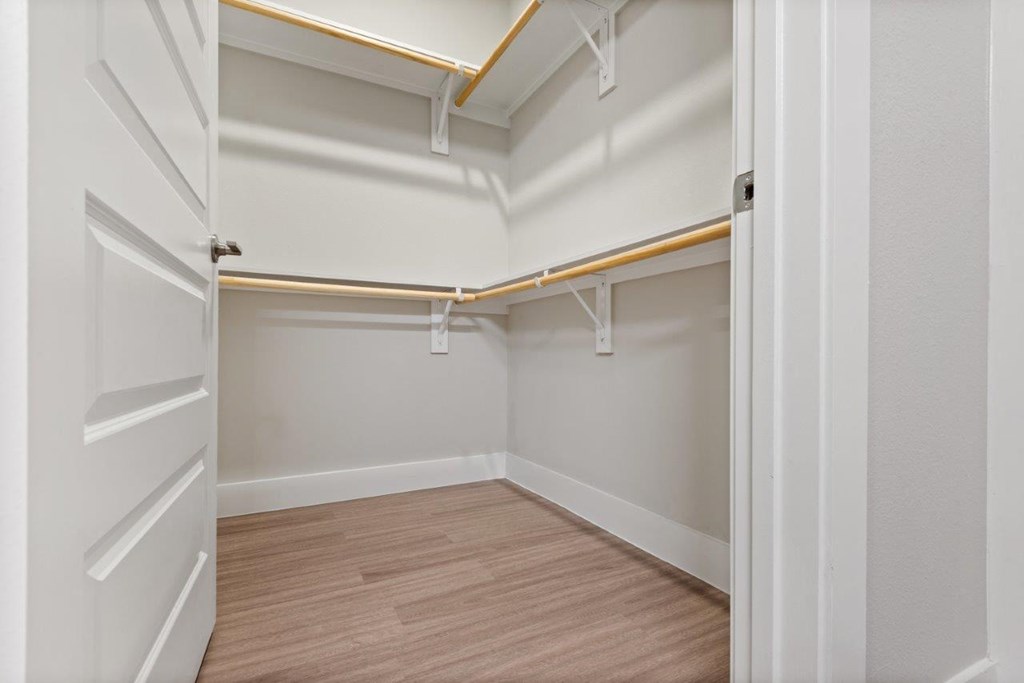 an empty closet with white walls and a wood floor