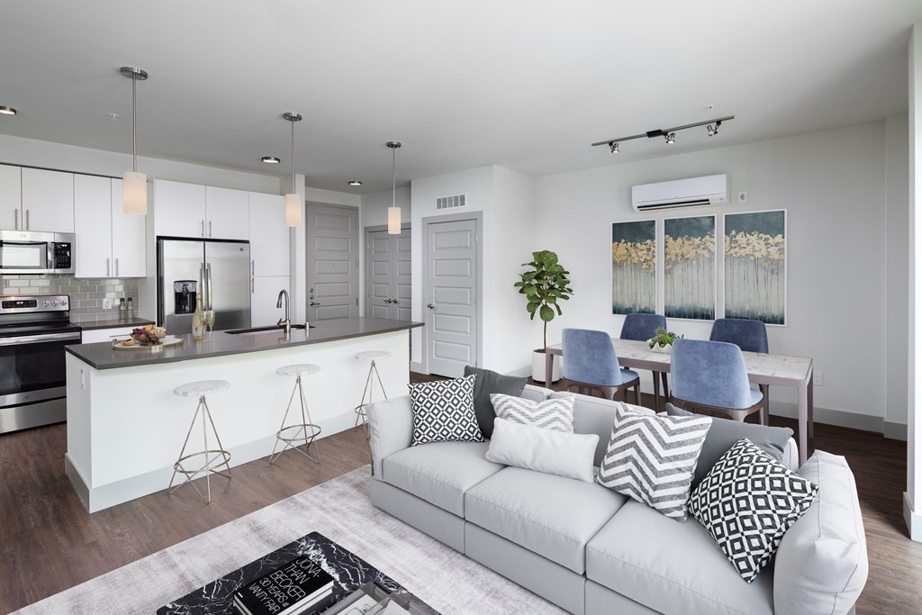 a living room with a white couch and a kitchen with a bar