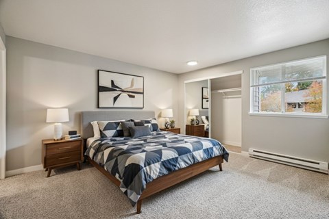 A bedroom with a large bed and a window showing trees outside.