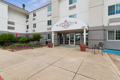 The entrance to the Maverick apartment complex is shown with a red flower in a pot.