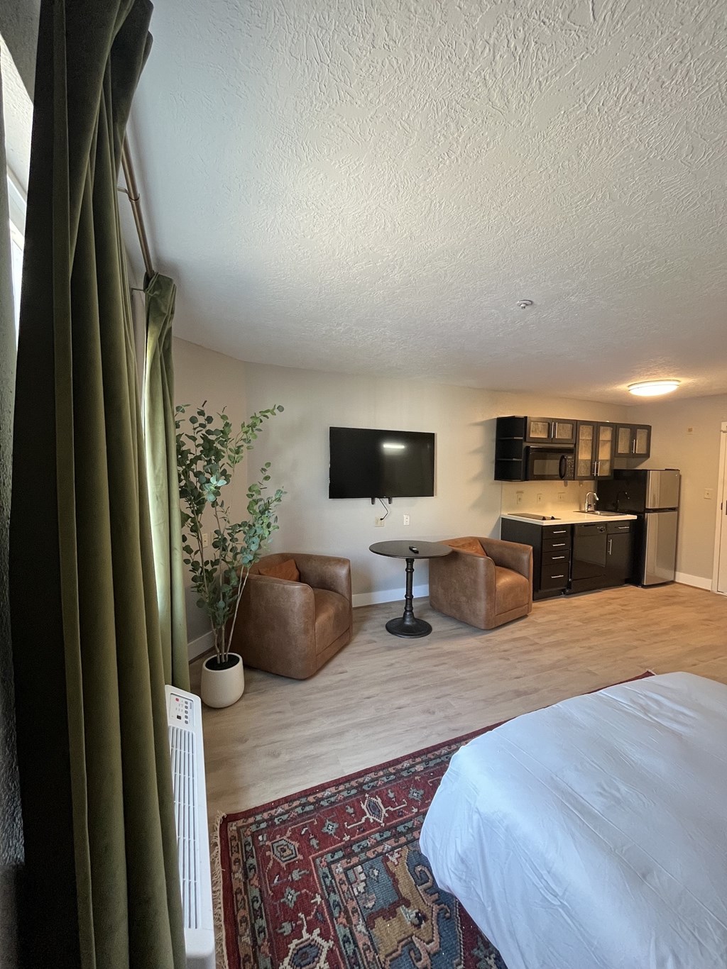 A bedroom with a bed, a chair, a table, and a TV.