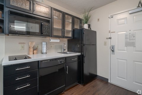 A black fridge and oven in a kitchen with white cabinets.