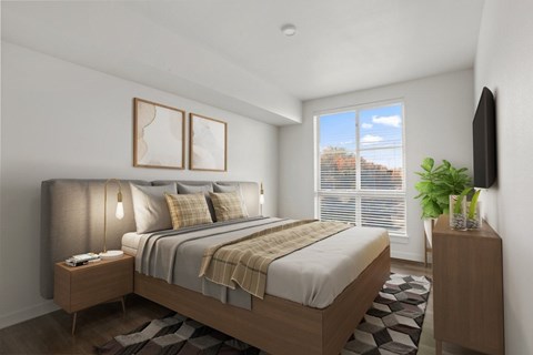 A bedroom with a large bed, a nightstand with a lamp, and a TV on the wall.