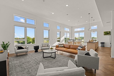 a living room with couches and chairs and large windows