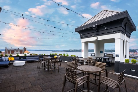 a rooftop patio with tables and chairs and a view of the water