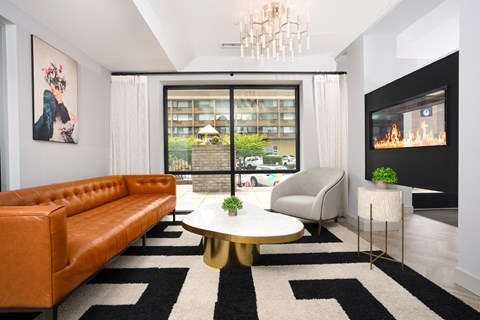 A living room with a brown leather couch, a white coffee table, and a chandelier.