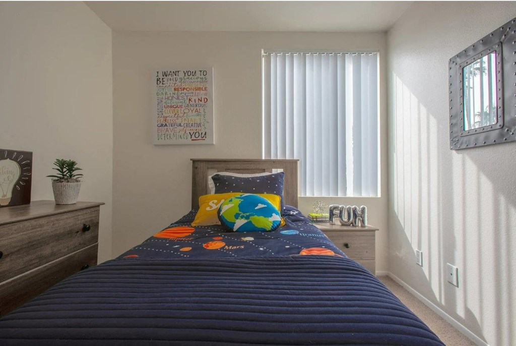 a bedroom with a bed with a blue comforter   and a window