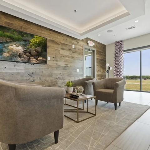 A living room with a large painting of a river on the wall.
