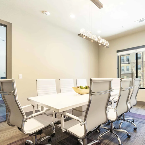 A conference room with a white table and chairs.