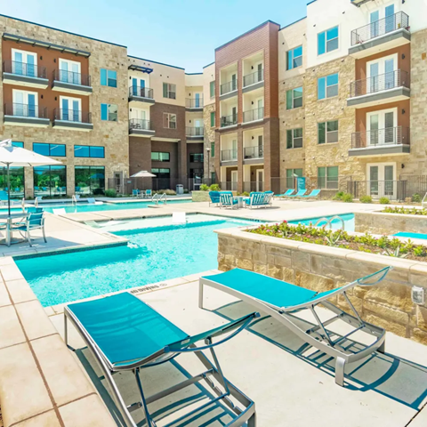 A pool area with sun loungers and a stone building in the background.