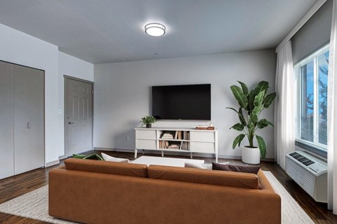 A living room with a brown couch and a flat screen TV mounted on the wall.