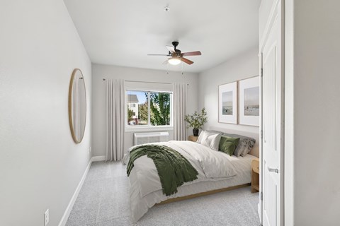A bedroom with a bed, a mirror, a window with curtains, and a ceiling fan.