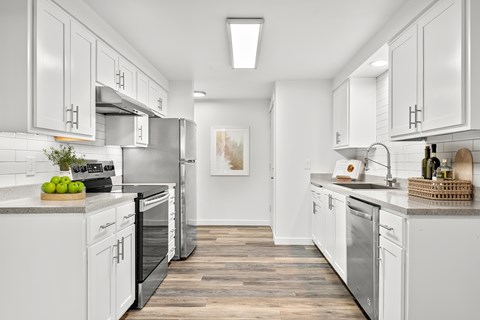 A modern kitchen with white cabinets and stainless steel appliances.