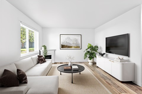 A living room with a white couch, a coffee table, and a painting on the wall.