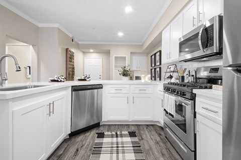 a white kitchen with stainless steel appliances and white cabinets