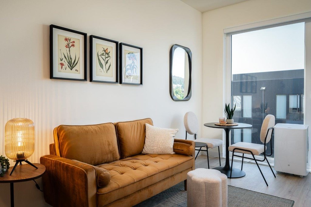 MERX Slabtown living room with a brown couch, a small table, and a round mirror on the wall.