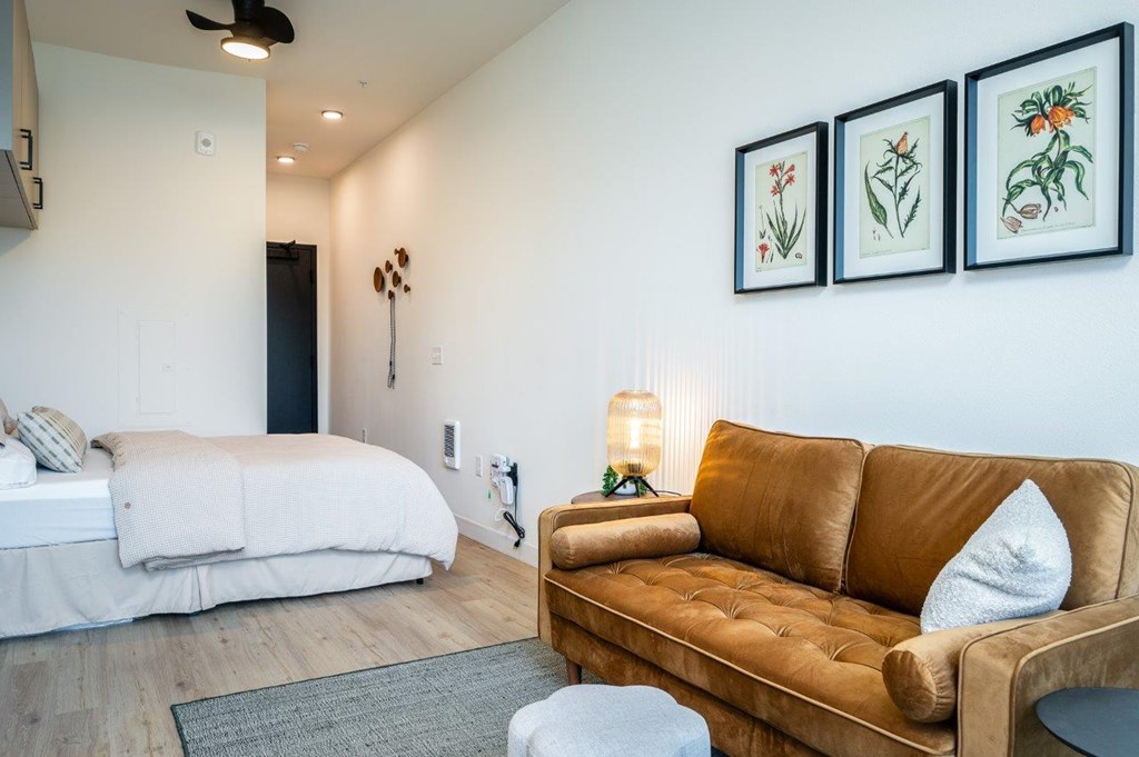 MERX Slabtown brown couch sits in a living room with a white bed in the background.