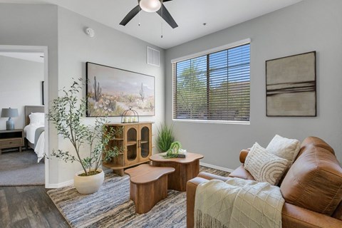 A living room with a brown leather couch, a wooden coffee table, and a painting on the wall.