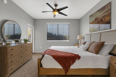 A bedroom with a bed, dresser, and ceiling fan.