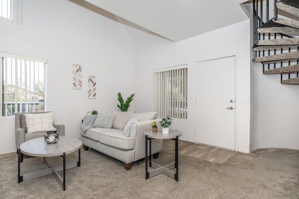 A living room with a white couch, a coffee table, and a staircase.
