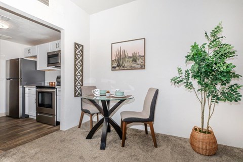 A dining area with a table and chairs and a potted plant.
