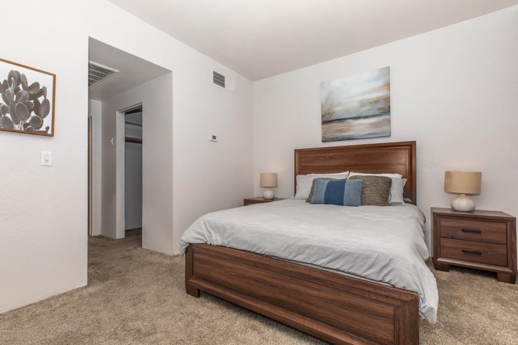 A bedroom with a bed, nightstands, and a painting on the wall.