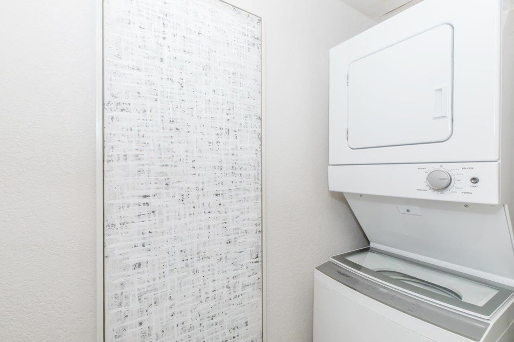 A white dryer is next to a white wall with a list of items on it.