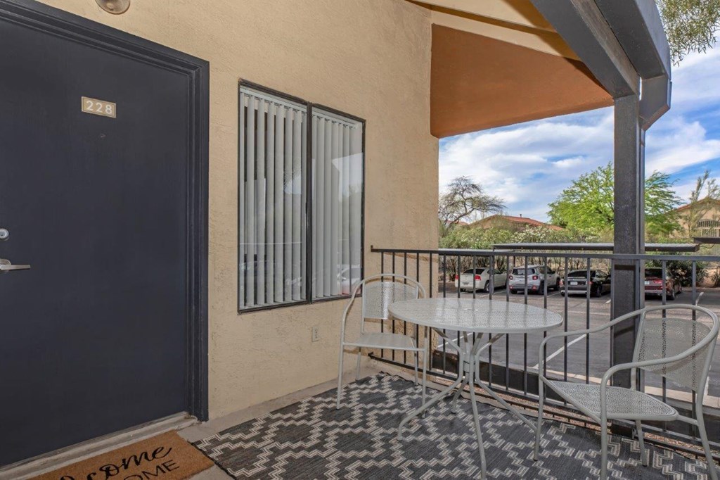 A balcony with a table and chairs overlooking a parking lot.