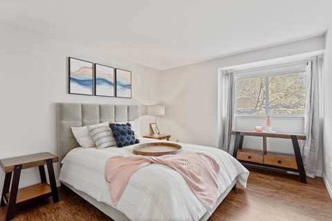A bedroom with a large bed and a window overlooking a tree-lined street.