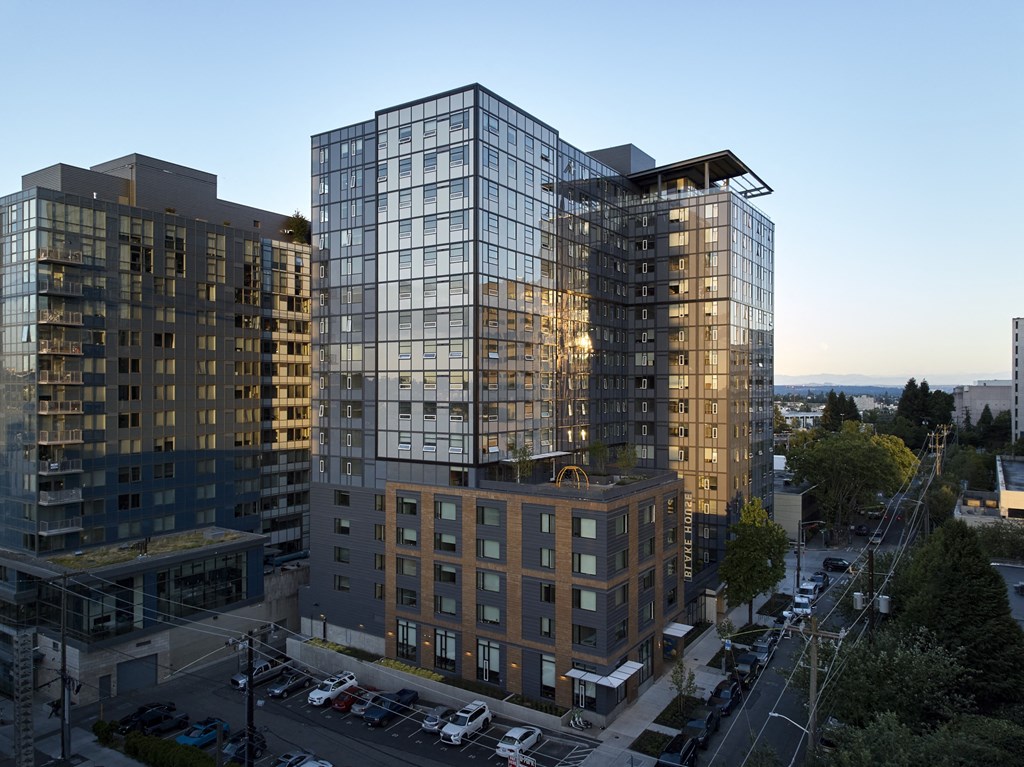 an aerial view of a tall glass and brick building with a flat roof and other buildings in