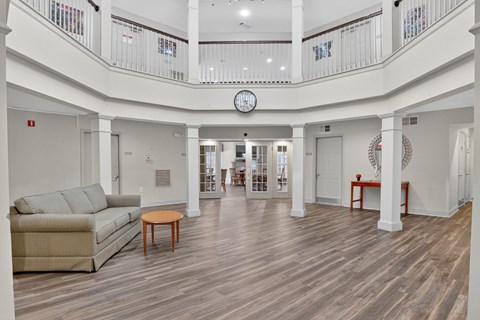 A living room with a couch, a table, and a clock on the wall.
