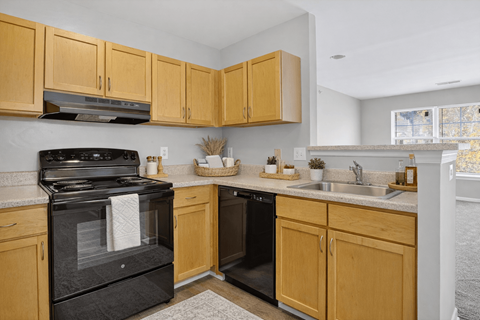 A kitchen with wooden cabinets and a black stove top oven.