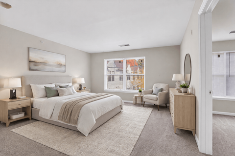 A bedroom with a large bed and a chair by the window.