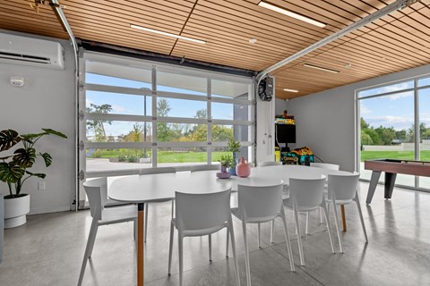 a dining room with white tables and chairs and large windows